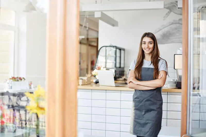 Emprendedora con delantal al frente de una pequeña cafetería